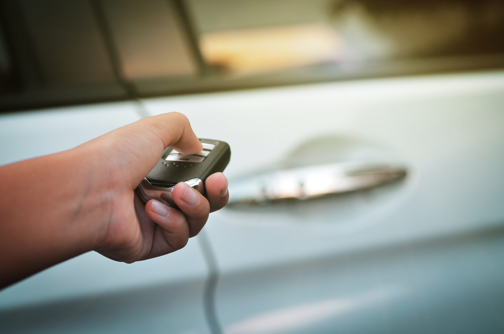 Hand pressing the button on the remote to lock or unlock the car, Open the car door with the remote control.